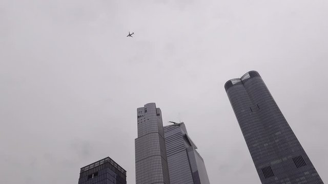 Jetliner flying over modern office towers Manhattan NYC overcast day
