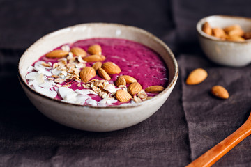 Purple berry smoothie with coconut flakes, oats and almond nuts.