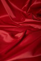 close up view of red soft and crumpled silk textured cloth