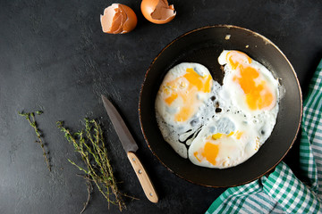 eggs in a pan , towel, knife, thyme, shell on a black background