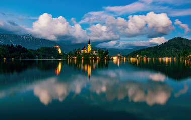 Magnificent view of Bled lake and illuminated pilgrimage church on island at twilight reflected in water, Slovenia