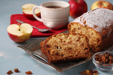 Homemade muffin with semolina, apples and raisins on a metal tray on a light blue background and cup of coffee