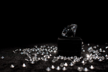 Diamond near gemstones on black velour isolated on black