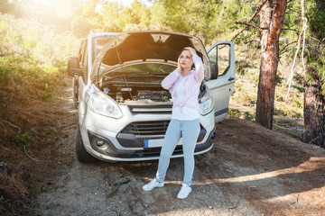 Woman is waiting desperately with open car hood for support of troubleshoot automobile. Transportation and vehicle concept.