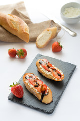 Bruschette con feta e fragole, sfondo bianco. 