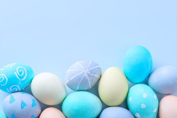 Colorful Easter eggs dyed by colored water with beautiful pattern on a pale blue background, design concept of holiday activity, top view, copy space.