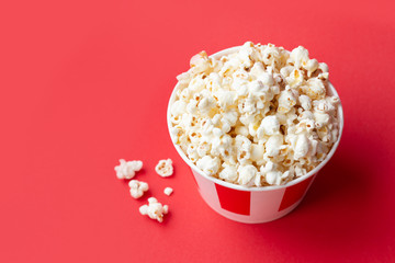 popcorn in a paper striped box on a red background with copy space. American food background. Red background. Fast food.