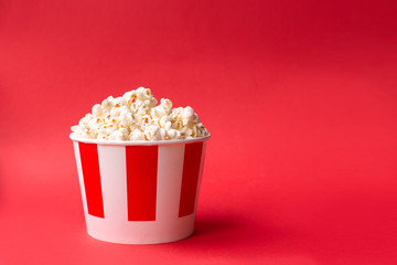 popcorn in a paper striped box on a red background with copy space. American food background. Red background. Fast food.
