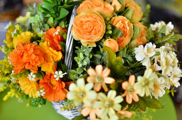 Bouquet of multicolored artificial flowers to the basket.