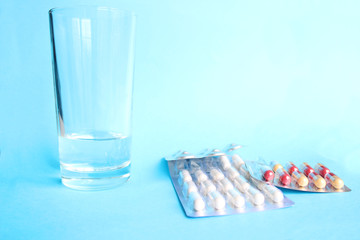 Glass of water and pills isolated on blue