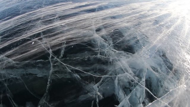 Snow blowing on ice from a strong wind on Lake Baikal in winter at sunset, Russia Siberia