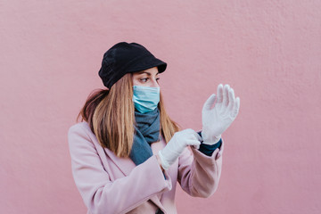 caucasian woman in the street wearing protective gloves and using mobile phone. corona virus concept