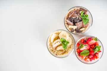 Set various fruit overnight oatmeal. Oats porridge with strawberry, bananas, chocolate, nuts in small portion jars. Summer breakfast oatmeal. Healthy vegan diet snack.