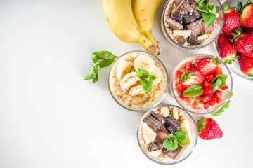 Set various fruit overnight oatmeal. Oats porridge with strawberry, bananas, chocolate, nuts in small portion jars. Summer breakfast oatmeal. Healthy vegan diet snack.