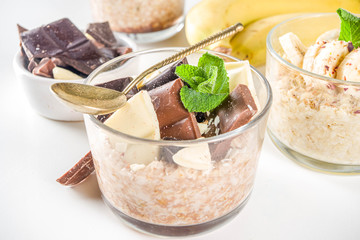Set various fruit overnight oatmeal. Oats porridge with strawberry, bananas, chocolate, nuts in small portion jars. Summer breakfast oatmeal. Healthy vegan diet snack.