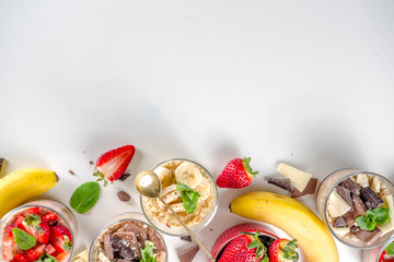 Set various fruit overnight oatmeal. Oats porridge with strawberry, bananas, chocolate, nuts in small portion jars. Summer breakfast oatmeal. Healthy vegan diet snack.