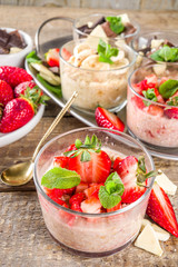 Set various fruit overnight oatmeal. Oats porridge with strawberry, bananas, chocolate, nuts in small portion jars. Summer breakfast oatmeal. Healthy vegan diet snack.