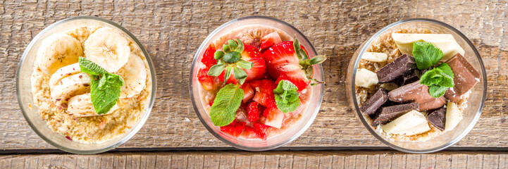 Set various fruit overnight oatmeal. Oats porridge with strawberry, bananas, chocolate, nuts in small portion jars. Summer breakfast oatmeal. Healthy vegan diet snack.