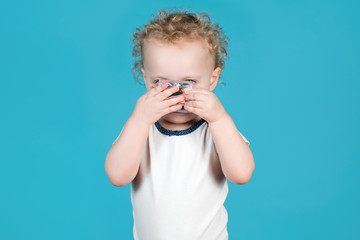 Two-year-old curly baby girl puts a condom on her face