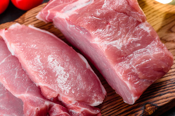 Fresh pieces pork ready to cook on a dark background in the kitchen