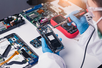 The abstract image of the technician assembling inside of smartphone by screwdriver in the lab. the...