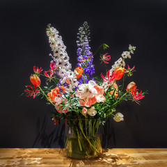 Luxury Bouquet of Mixed Flowers in Glass Vase on Wooden Table Surface Against Dark Grey Background. Still life or Wedding Decor.