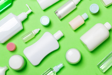 Top view of different cosmetic bottles and container for cosmetics on green background. Flat lay composition with copy space