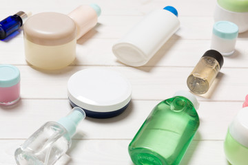 Close-up view of cosmetic bottles, jars, containers and sprays on white wooden background. Beauty concept with copy space