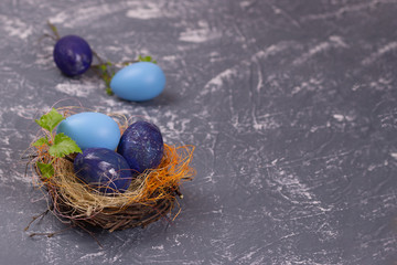 Blue easter eggs in a nest on a gray background. Selective focus. Copy space