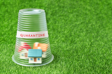 Coronavirus quarantine concept. Small house covered with transparent plastic cup and inscription...
