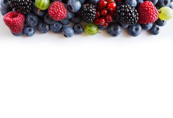 Mixed berries on a white background. Top view. Fruits and berries at border with copy space for text. Blue-black and red food.