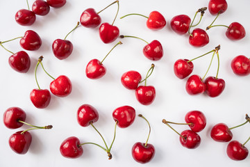 Fresh cherries scattered on white. Cherry fruit. Creative fresh cherry pattern background with copy space. Top view. Sprinkled cherry on white background. Isolated fruit.