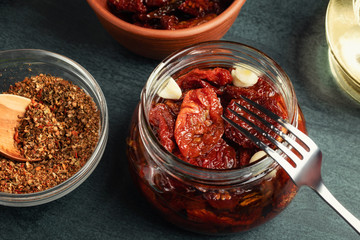 Cooking sun-dried tomatoes in a glass jar with olive oil, garlic and spices