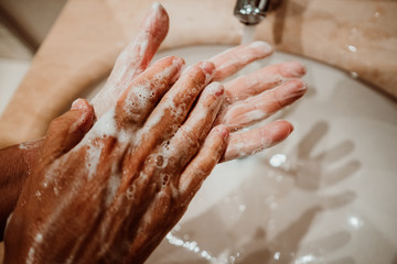 Middle-aged woman washing her hands with soap and water to avoid contagion of the coronavirus. Health risk prevention. Healthcare