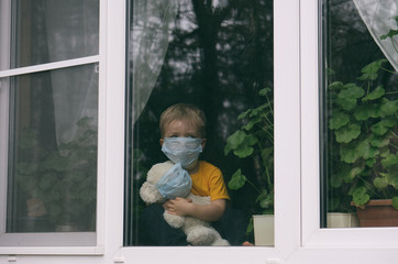 Child wearing face mask hugs teddy bear