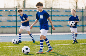 Soccer Training Exercises for Kids. Boys Training with Balls on Summer Football Grass Field. Young Sporty Kids in a Team with Coach. Practice Soccer Unit for School Children. Stadium in the Background