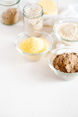 Various gluten free flour corn,sesame,oat,coconut in glass bowl on white background.Alternative to wheat flour for keto paleo diet.Healthy eating,dieting,balanced food concept.Copy space,top view
