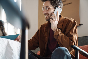 Image of young man writing down notes while talking on cellphone in cafe