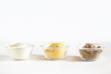 Various gluten free flour corn,sesame,oat,coconut in glass bowl on white background.Alternative to wheat flour for keto paleo diet.Healthy eating food concept.Copy space,horizontal orientation