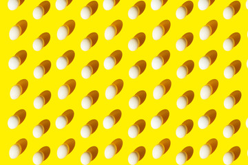 Trendy easter pattern of white easter eggs in bright light with shadows on a yellow background. Minimal concept