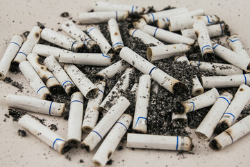 Cigarette butts on a plate. Smoked cigarettes.