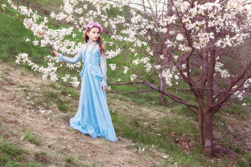 Obraz na płótnie Canvas Portrait of a beautiful girl in a long dress in a magnolia garden.