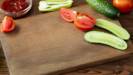 Wooden cutting board with tomatoes, cucumbers and empty space
