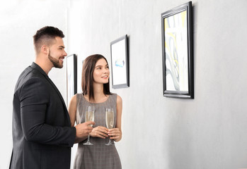 Young couple at exhibition in modern art gallery