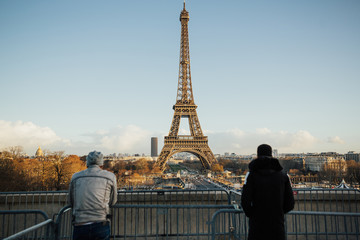 Fototapeta na wymiar Back view of young travel men on the area Trocadero with Eiffel tower on background. Young men stands and looks at the Eiffel Tower in Paris.