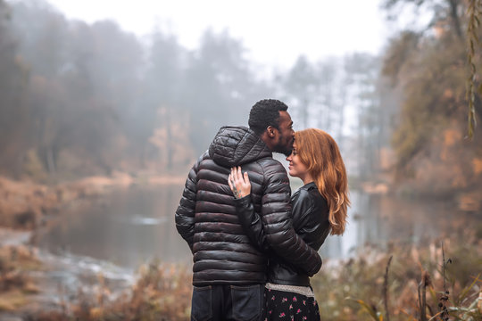Interracial couple posing in autumn leaves background