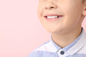 Happy little boy with healthy teeth on color background, closeup