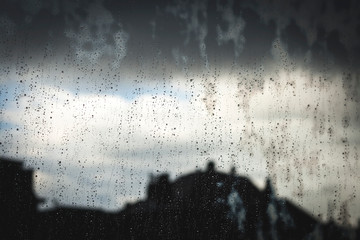 raindrops in a window glass, stormy urban landscape background
