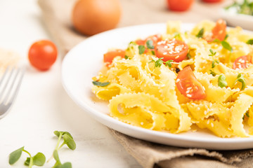 Reginelle semolina pasta with tomato, eggs, sesame and microgreen sprouts on a white wooden background. Side view, selective focus.