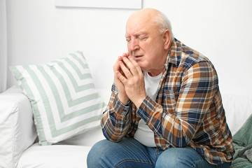 Portrait of elderly man praying at home